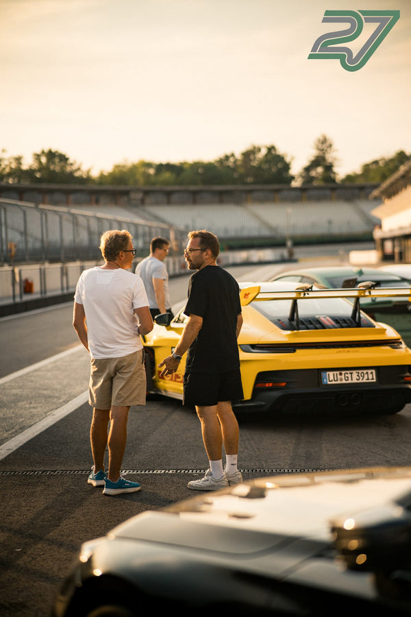 Zwei Männer sprechen im goldenen Abendlicht neben einem gelben Porsche 911 GT3 RS