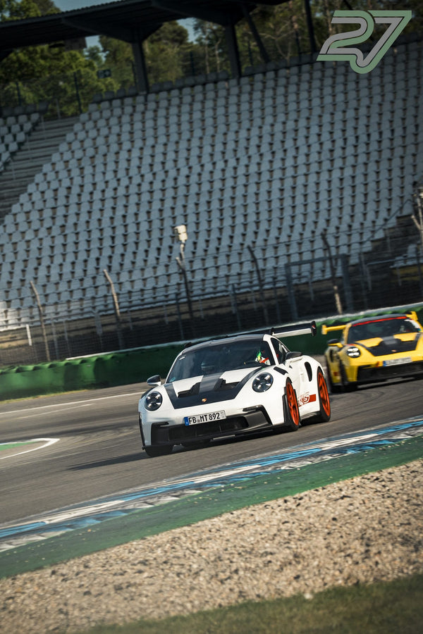 Weiß-roter Porsche 911 GT3 führt gelben Porsche 911 GT3 durch die schnelle Kurve an