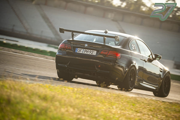 Schwarzer BMW M3 mit Startnummer 21 fährt im goldenen Gegenlicht durch die Kurve