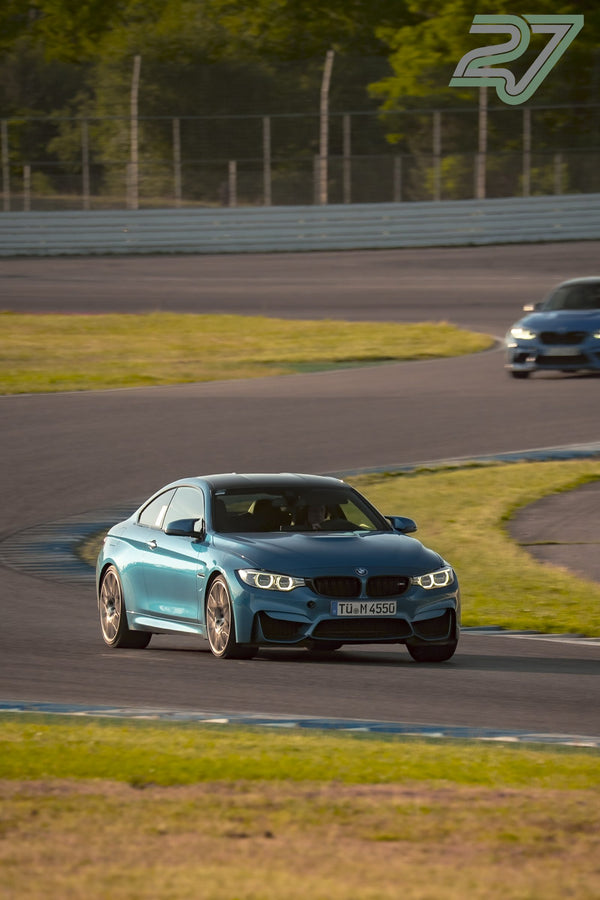 Petrolfarbener BMW M4 fährt mit eingeschlagenen Rädern frontal durch die Kurve