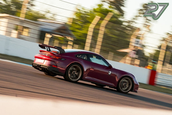 Bordeauxroter Porsche 911 GT3 mit Startnummer 3 neigt sich in einer schnellen Kurve