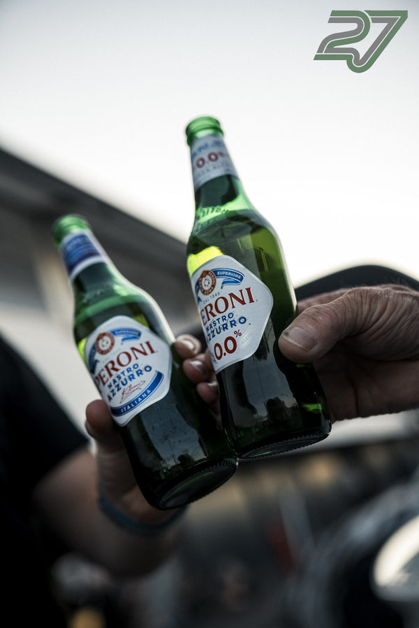 Zwei Hände stoßen im hellen Gegenlicht mit alkoholfreien Bierflaschen aneinander an