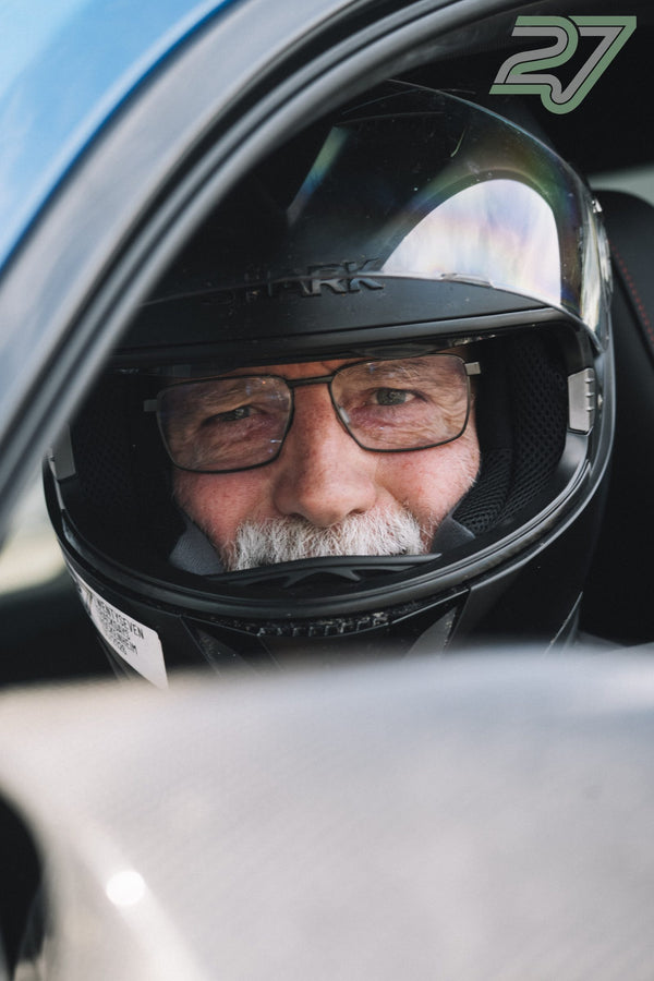 Fahrer mit Helm, Brille und weißem Bart blickt direkt in die Kamera, das Visier spiegelt
