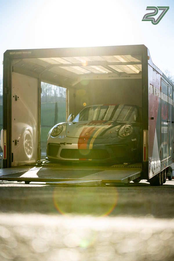 Heller Porsche 911 mit Mittelstreifen steht im offenen Transportanhänger, Gegenlicht im Laderaum