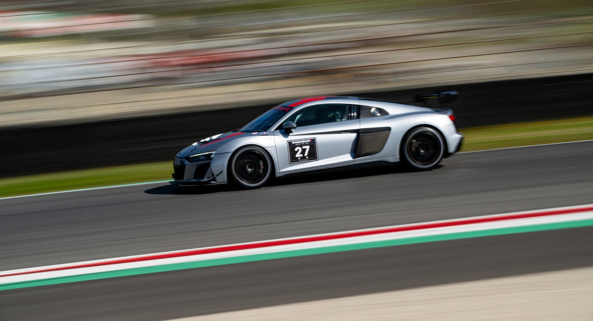 Weißer Audi R8 LMS mit Startnummer 29 im Mitzieher vor der langen Mugello-Haupttribüne