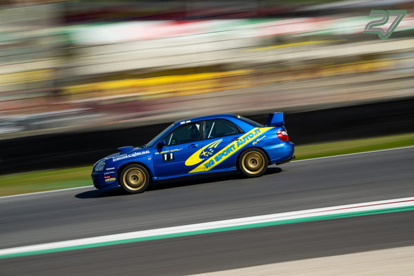 Goldfelgen und Startnummer 11 am blauen Subaru Impreza, scharf gezogen vor verwischter Kulisse