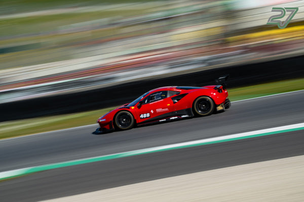 Roter Ferrari 488 Challenge zieht scharf gezeichnet vor komplett verwischter Streckenkulisse vorbei