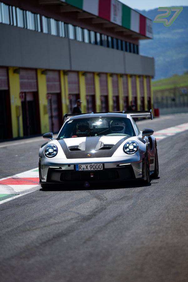 Silbergrauer Porsche 911 GT3 RS mit großem Heckflügel steht frontal vor dem Boxengebäude
