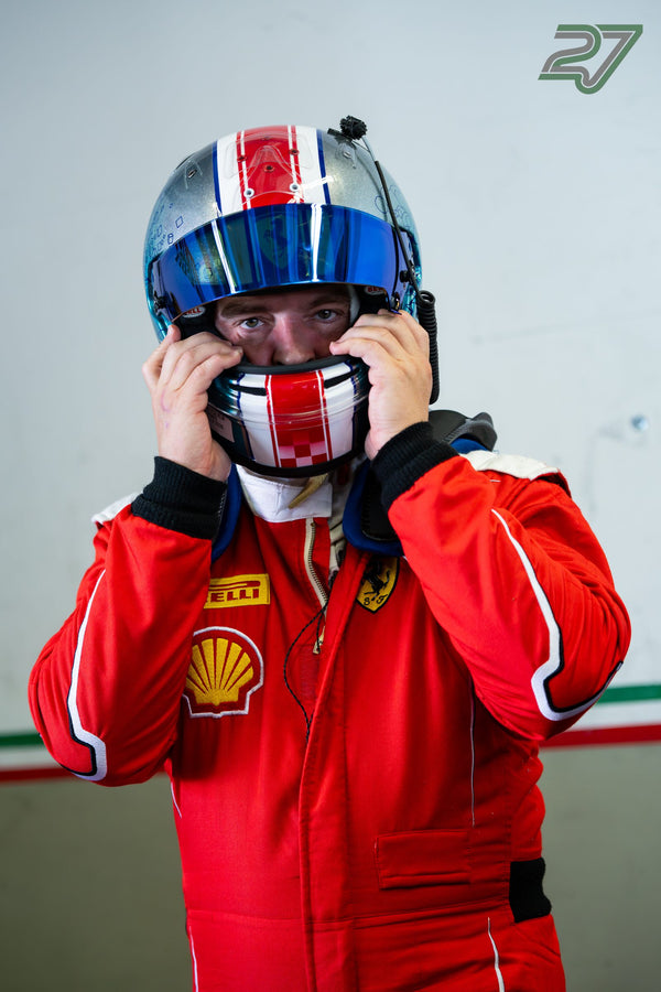 Ein Fahrer im roten Rennanzug zieht sich den silbern-rot-blauen Helm über, Hände am Kinnbügel