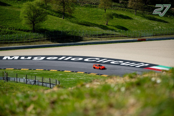 Oranger Porsche 911 GT3 auf der Strecke, darüber der große Schriftzug MugelloCircuit im Auslauf