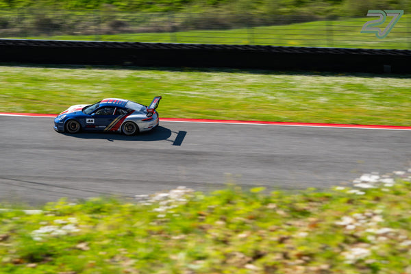 Blau-silberner Porsche 911 GT3 Cup mit Startnummer 46 im Mitzieher am roten Randstein