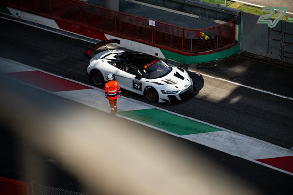 Weißer Audi R8 mit Startnummer 29 an der Boxenausfahrt, daneben ein Streckenposten in Orange