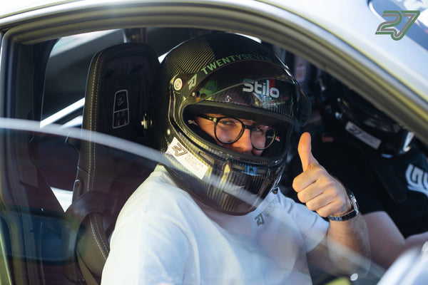 Daumen hoch aus dem Cockpit: Fahrer mit Carbonhelm und Brille hinter der Seitenscheibe