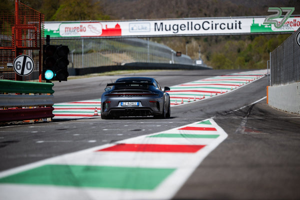 Grauer Porsche 911 GT3 von hinten an der Boxenausfahrt unter dem MugelloCircuit-Banner, grüne Ampel