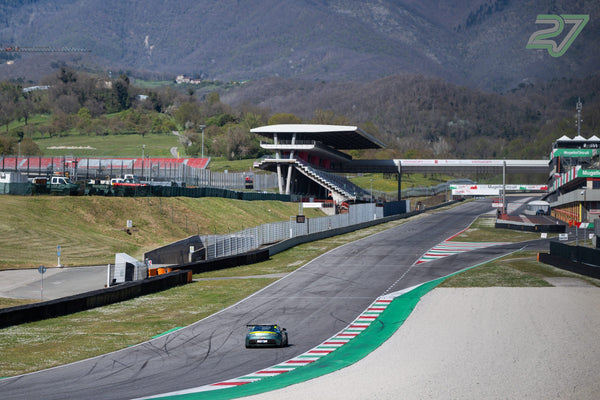 Grüner Aston Martin Vantage entfernt sich Richtung Tribüne, Bergkette über dem Mugello-Rund