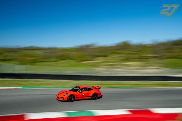 Im Mitzieher schießt ein orangefarbener Porsche 911 GT3 mit Nummer 16 durch die Kurve