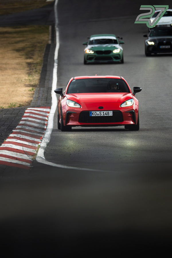 Roter Sportwagen fährt frontal durch die Kurve, dahinter folgen weitere Rennfahrzeuge