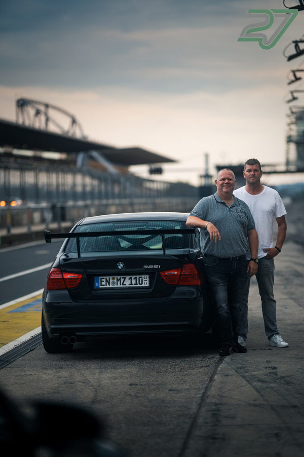 Zwei Männer stehen neben schwarzem BMW 3er mit Heckflügel in der Boxengasse am Nürburgring