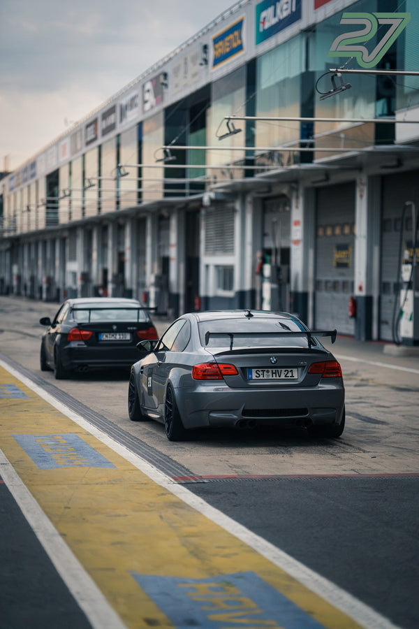 Grauer BMW M3 mit Startnummer folgt einem schwarzen BMW durch die Boxengasse