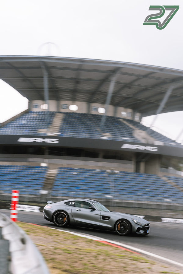 Silberner Mercedes-AMG GT mit orangefarbenen Bremssätteln zieht vor der Tribüne vorbei