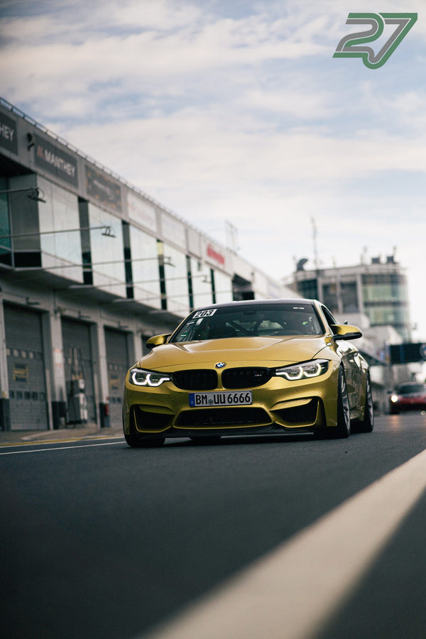 Goldgelber BMW M4 rollt bei Sonnenschein durch die Boxengasse des Nürburgrings