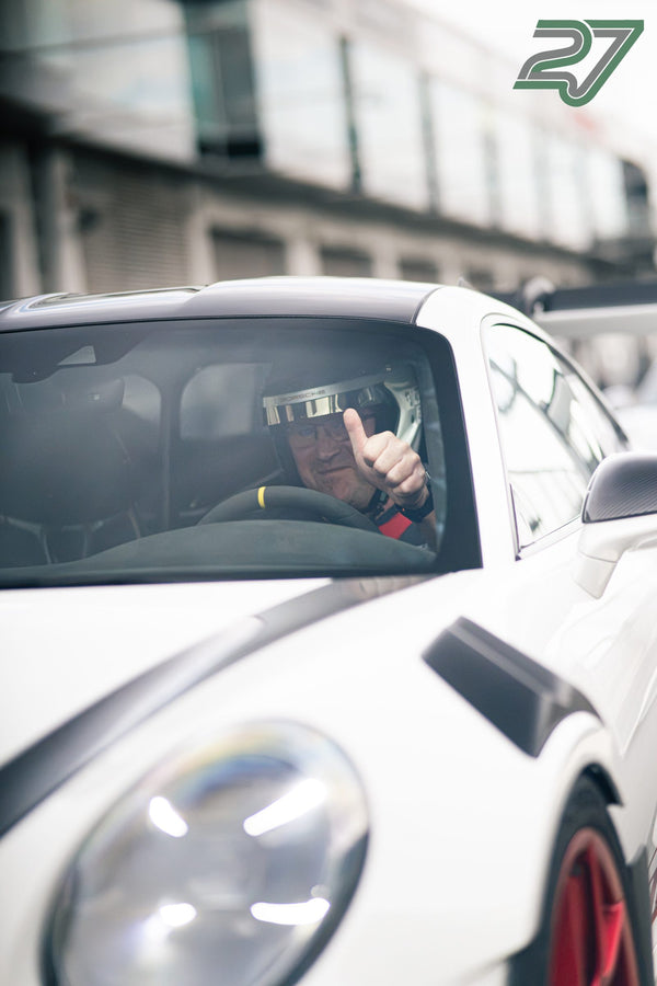 Fahrer im weißen Porsche lächelt hinter der Scheibe und zeigt den Daumen hoch