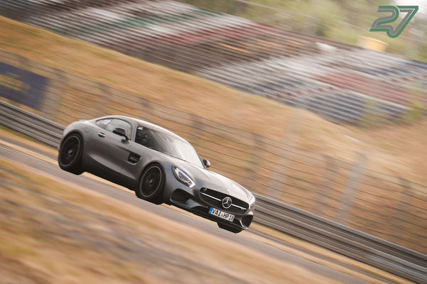 Dunkelgrauer Mercedes-AMG GT rast in scharfer Schräglage die Strecke hinunter
