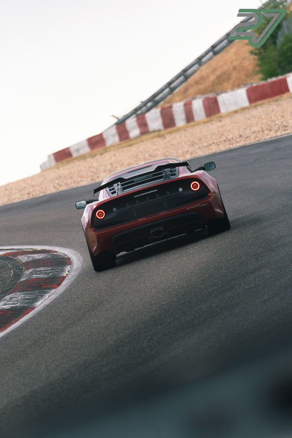 Dunkelroter Lotus Exige fährt mit dem Heck zur Kamera durch eine enge Steilkurve
