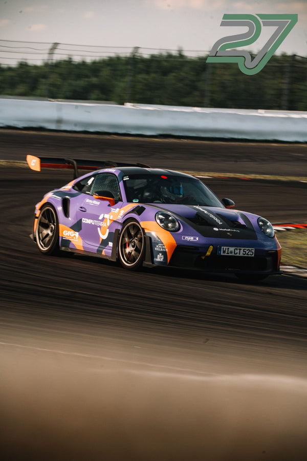 Lila-oranger Porsche 911 Cup-Rennwagen fährt dynamisch durch eine enge Kurve