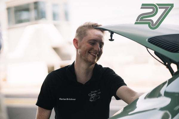 Lächelnder Mann steht an einem mintgrünen Oldtimer-Porsche mit geöffneter Heckklappe