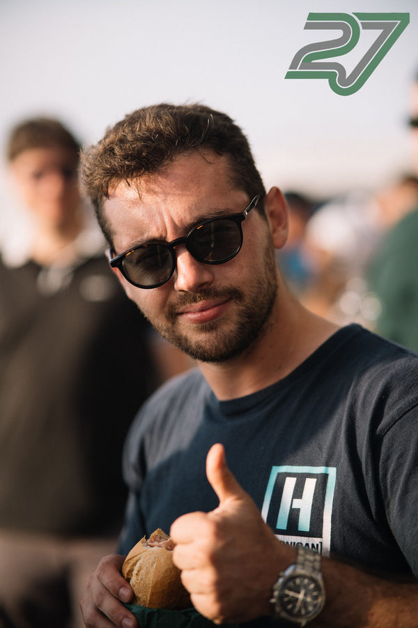 Mann mit Sonnenbrille hält ein belegtes Brötchen und zeigt lachend den Daumen hoch