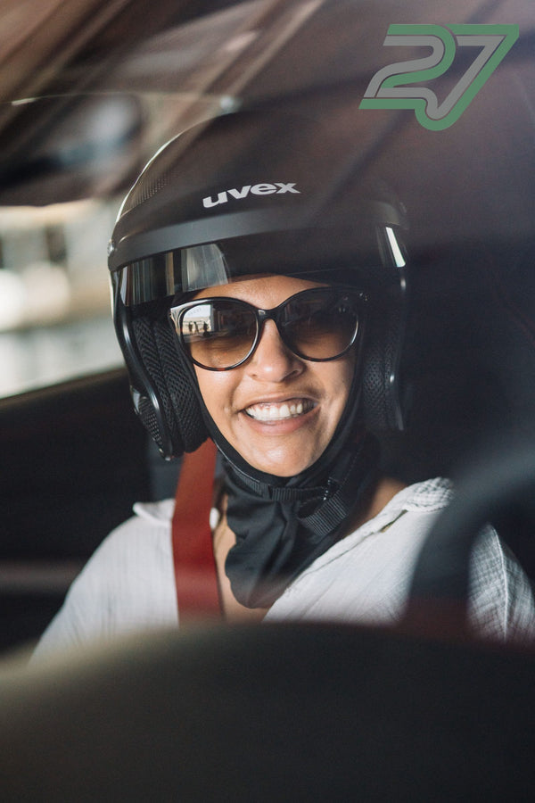 Fahrerin mit schwarzem Helm und dunkler Sonnenbrille lächelt breit im Fahrzeug