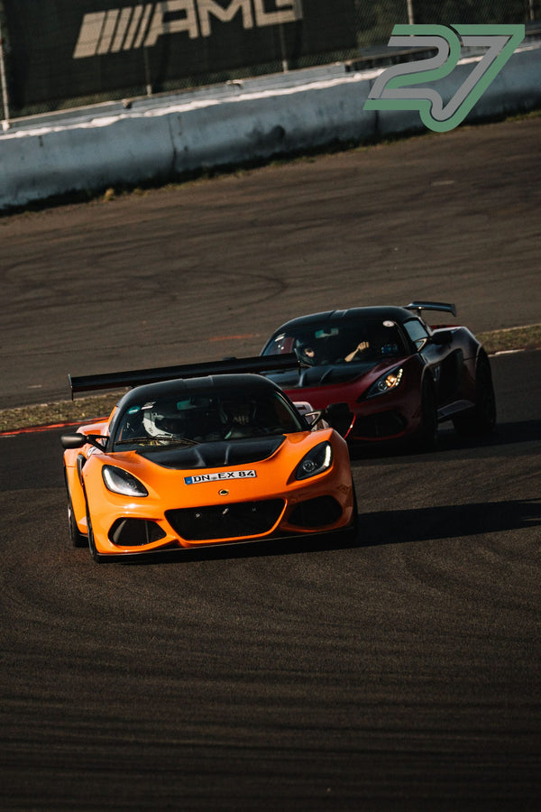 Zwei Lotus Exige fahren orange vor dunkelrot hintereinander durch eine Kurve der Strecke