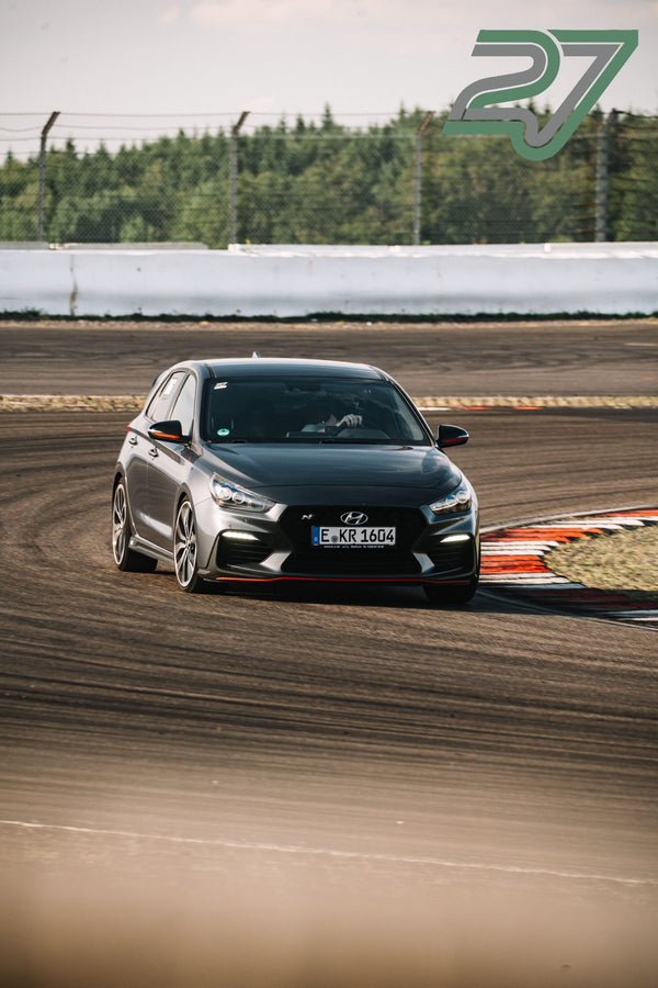 Grauer Hyundai i30 N fährt in Frontalansicht durch eine enge Kurve der Strecke