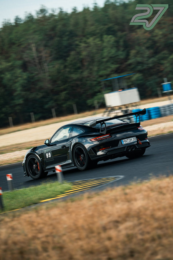 Schwarzer Porsche 911 GT3 mit Startnummer 99 fährt schnell aus einer Waldkurve heraus