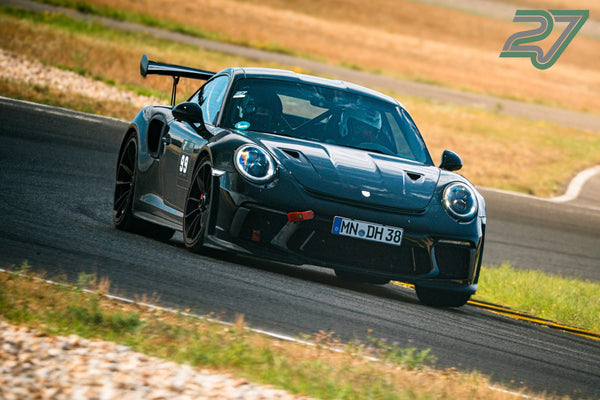 Dunkelgrauer Porsche 911 GT3 mit Startnummer 99 kommt frontal aus einer schnellen Kurve