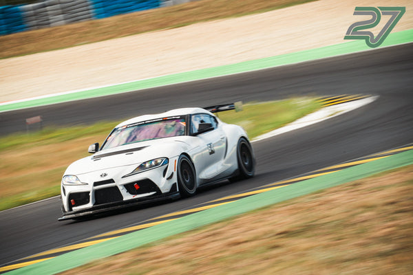 Weißer Toyota Supra Rennwagen kurvt mit kräftiger Bewegungsunschärfe durch eine schnelle Passage