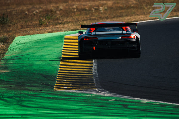 Weiß-roter Audi R8 GT3 wirkt im Gegenlicht wie schwebend über dem Curb, Rücklichter leuchten rot