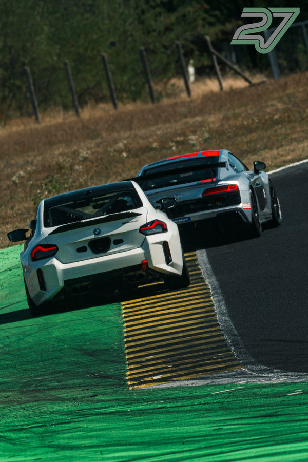 Weißer BMW M2 Rennwagen führt knapp vor einem silbernen Audi R8 GT3 über eine Bodenwelle