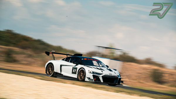 Weiß-schwarzer Audi R8 fährt im Profil an einem Hang vorbei, Hintergrund stark verwischt