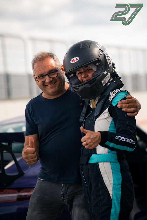 Mann legt lächelnd den Arm um einen Fahrer im Rennoverall, beide zeigen den Daumen hoch