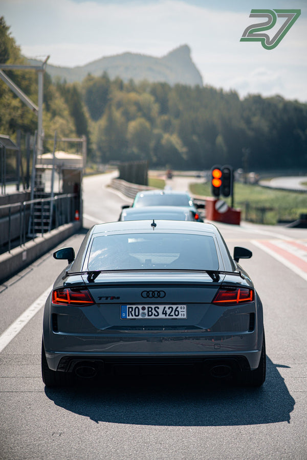 Grauer Audi TT RS wartet in der Fahrzeugschlange an der Ampel, dahinter erhebt sich das Bergpanorama