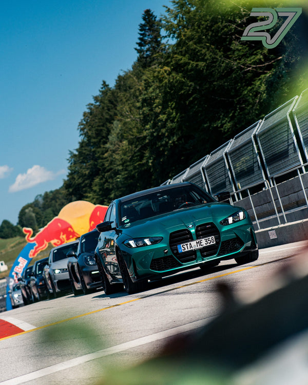 Türkisfarbener BMW M3 fährt am aufblasbaren Red-Bull-Torbogen vorbei in Richtung Kamera
