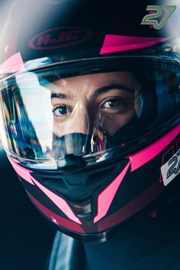 Extreme Nahaufnahme einer Person im pink-schwarzen Helm mit intensivem Blick durchs Visier