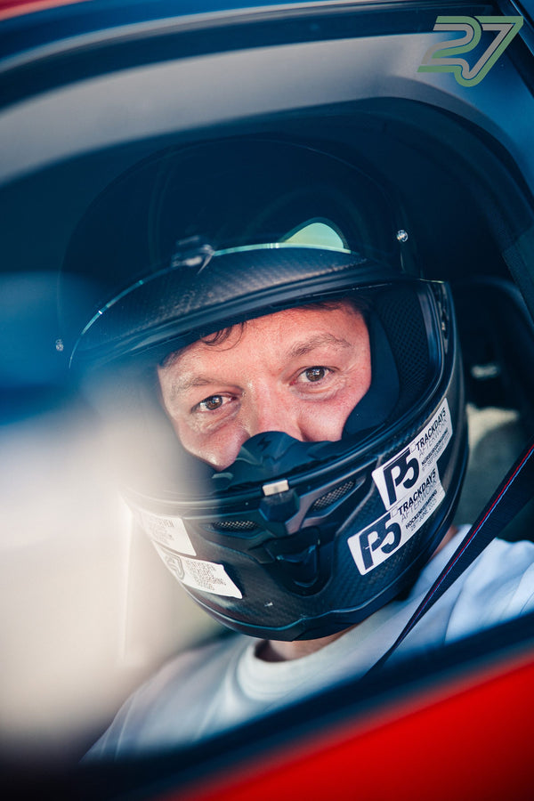 Nahaufnahme eines Fahrers im schwarzen Helm mit Trackday-Stickern und hochgeklapptem Visier