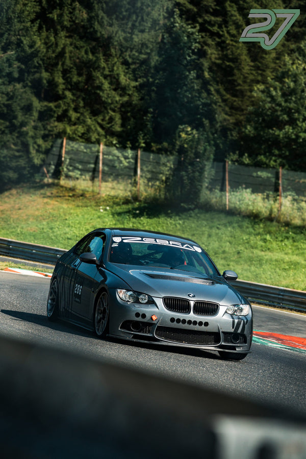 Der gestreifte BMW 3er mit Startnummer 286 kurvt im Schatten des Waldes um die Ecke