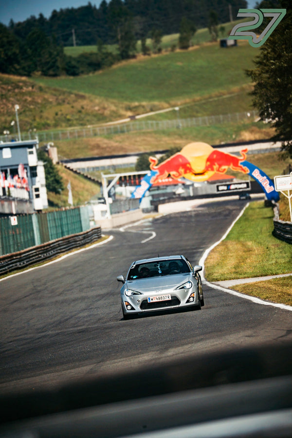 Silberner Toyota GT86 nähert sich allein dem Red-Bull-Bogen, das Boxengebäude im Hintergrund