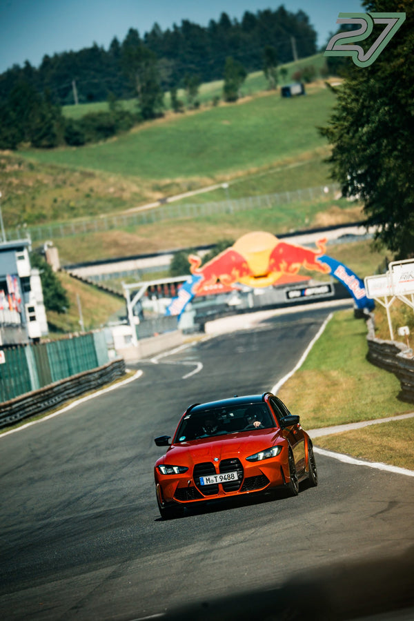 Oranger BMW M3 kommt den Hügel herunter, der Red-Bull-Bogen liegt noch ein Stück voraus