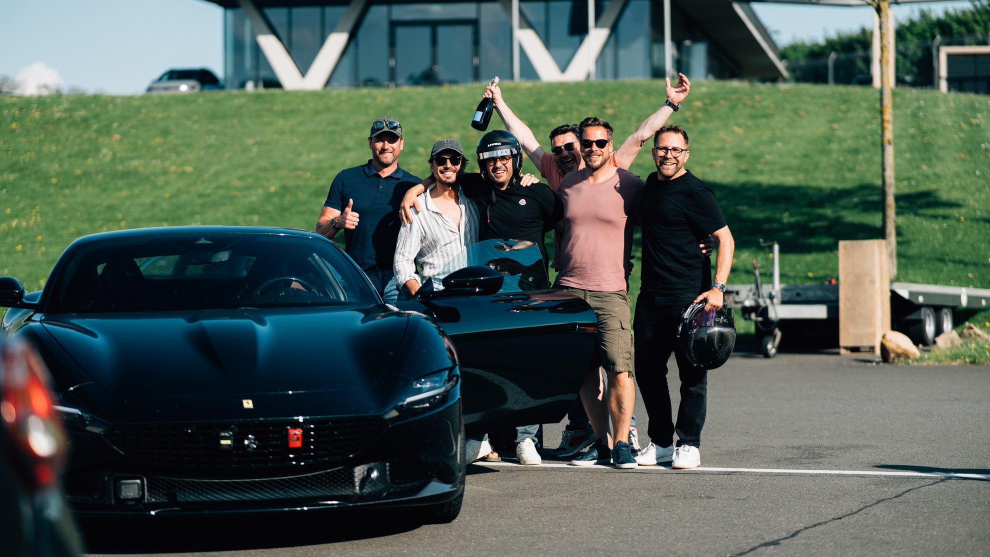 Eine glückliche Gruppe Männer bei einem Trackday neben einem Ferrari Roma am Bilster Berg.