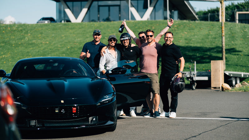 Group of participants in high spirits beside a Ferrari Roma at a trackday at the Bilster Berg
